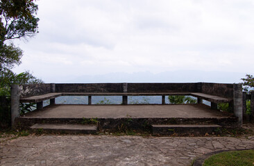 Natural stone and concrete podium in natural green background for Empty show for packaging product presentation. Concrete platform for view from top of mountain, sky and white clouds in background.