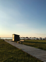 Obraz premium Peaceful beach boardwalk at sunset leading to tranquil waters