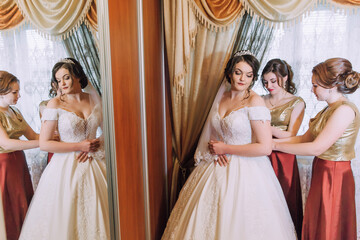 A bride and her bridesmaids are getting ready for the wedding. The bride is wearing a white dress...