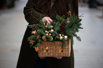 Very nice young woman holding big and beautiful winter festive composition of fresh Nobilis spruce