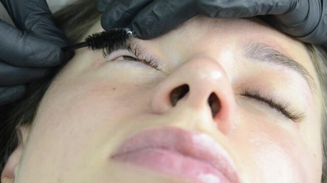 Eyelash extension procedure.Professional stylist lengthening female lashes.Eyelashes extensions. Fake eyelashes.Master and client in beauty salon.Close up.