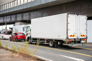 信号待ちしているパネルトラックと乗用車