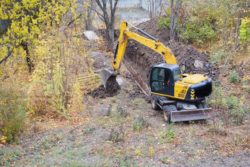 An excavator uncovering a trench with drainage pipes, maintenance work in public utilities, the excavator performing earthworks.