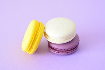 yellow, white and purple macarons next to a purple background