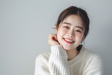 Portrait of a joyful Korean woman on a soft grey background.