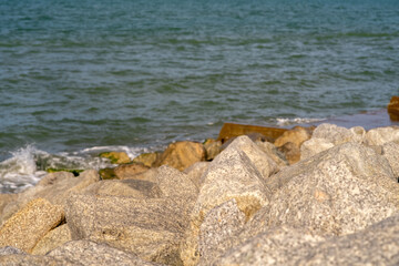 Coastal reinforcement with large grey granite rocks at seashore. Flood protection structure with huge stones. Beach stabilization construction