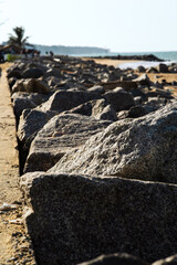 Coastal reinforcement with large grey granite rocks at seashore. Flood protection structure with huge stones. Beach stabilization construction