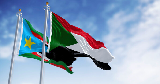 Sudan and South Sudan national flags waving in the wind on a clear day