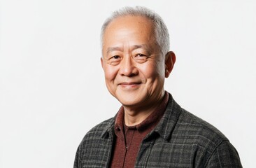 Obraz premium An elderly Asian man with gentle smile stands against solid gray background, embodying inner peace, happiness. His calm expression, relaxed posture capture naturally serene moment.