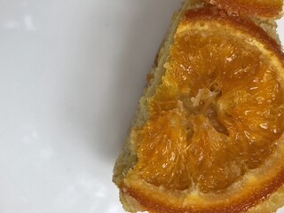A slice of cake topped with a vibrant orange, showcasing a rich, sweet texture and a delectable...