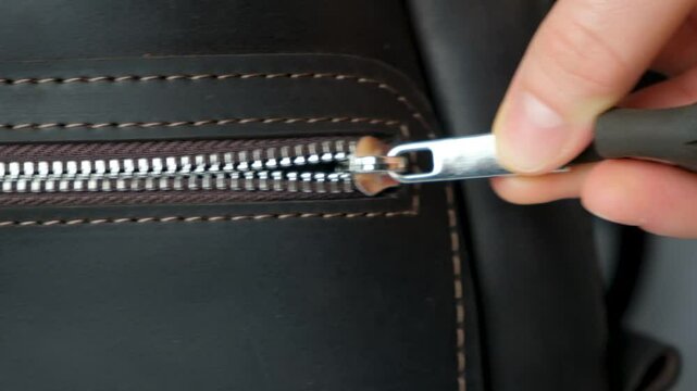 Unzipping leather backpack pocket slow motion macro.