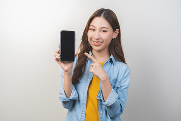 Naklejka premium Portrait of face expression smile charming brunette, happy asian young woman hand pointing, showing smartphone cell phone, mobile application in social network online on communication of technology.
