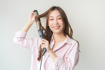 Beautiful curly brunette, attractive asian young woman, girl smiling using curler, curling iron...
