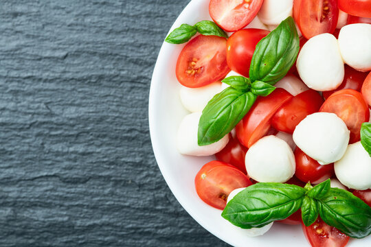 Basil leaves , cherry tomatoes and mozzarella cheese . In bowl food photography