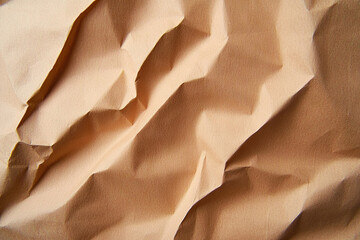 Crumpled brown paper texture with intricate folds and shadows, creating natural and organic feel. Ideal for backgrounds or artistic projects