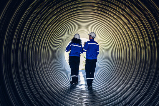 Industry Engineers Walking Inside Circular water Pipe. Engineering or Worker inspection pipe circular. Checking Construction of the water, Oil Natural Gas and fuels Transport Pipeline.
