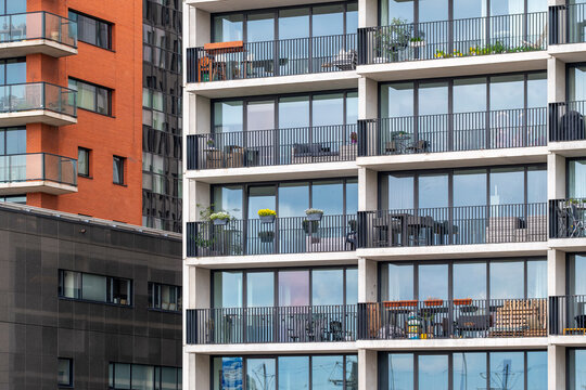 The image showcases a contemporary apartment building with decorated balconies adorned with plants and outdoor furniture, highlighting urban residential sophistication in Rotterdam