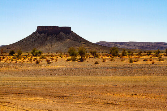 Dry stone desert and lonely table mountain in the background. Morocco