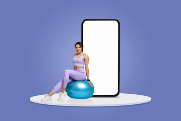 A woman dressed in purple activewear balances on a stability ball, engaging in fitness activities while a large smartphone stands behind her against a blue backdrop.