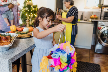 Mexican child girl holding a mexican pinata at home in Mexico celebrating traditional posadas for...