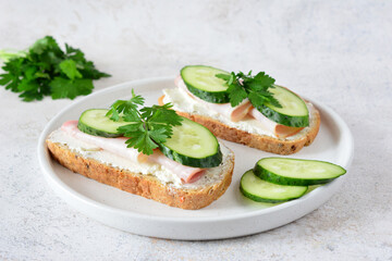 a sandwich with ham, cucumber and parsley on it