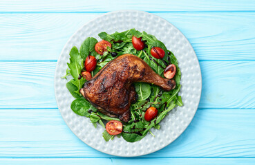 Grilled chicken legs with tomatoes and salad . Top view