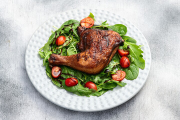 Grilled chicken legs with tomatoes and salad . Top view