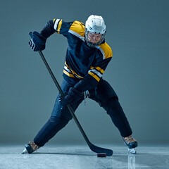 Focused man, ice hockey player captured in motion, powerfully skating across rink, holding stick....