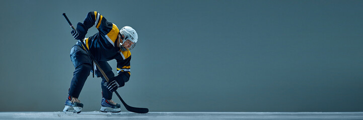 Focused man, hockey player in uniform and helmet, standing with puck, showing his readiness for the...