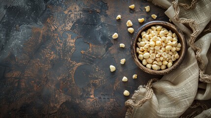 Rustic culinary composition with wooden bowl of macadamia nuts on textured surface for food design or cooking inspiration