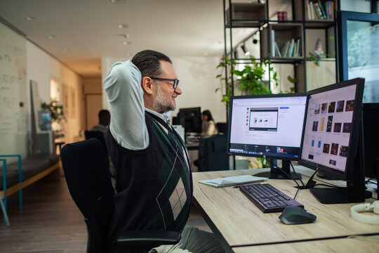 Man experiencing back pain while sitting at office desk with computer