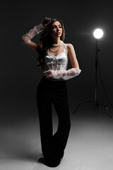 Portrait of a woman in a white blouse and with pearl beads in the spotlight in the studio.