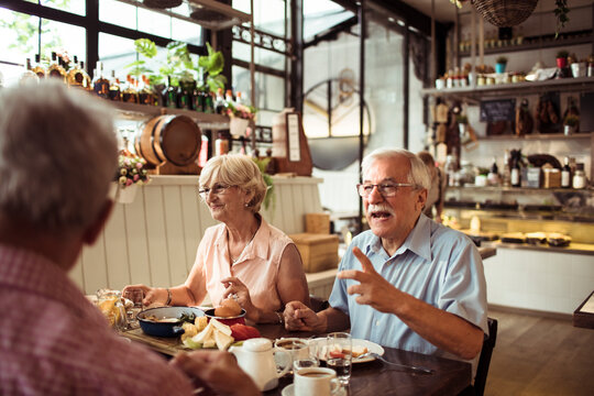 Happy senior friends eating at a cozy bistro together