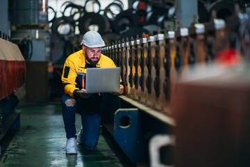 Fototapeta premium Engineers or supervisors inspecting and checking machines in a factory. Workers in the metal sheet industry carrying out their tasks.