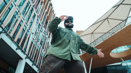 Low angle view of hipster pose in hip hop style surrounded by mall view. Portrait of sporty asian hip hop choreographer dancing break dance while looking at camera. Outdoor sport 2024. Hiphop.