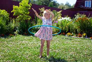 Little girl playing with hula hoop in her garden
