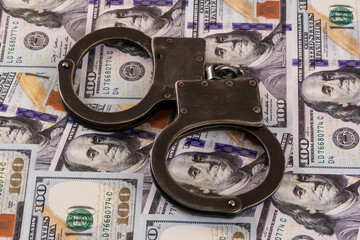 Handcuffs against the background of 100 US dollar bills