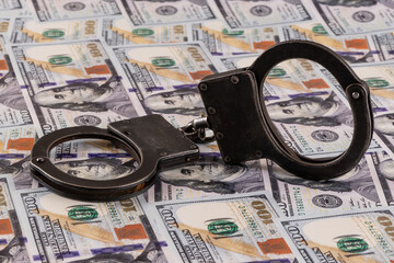 Handcuffs against the background of 100 US dollar bills