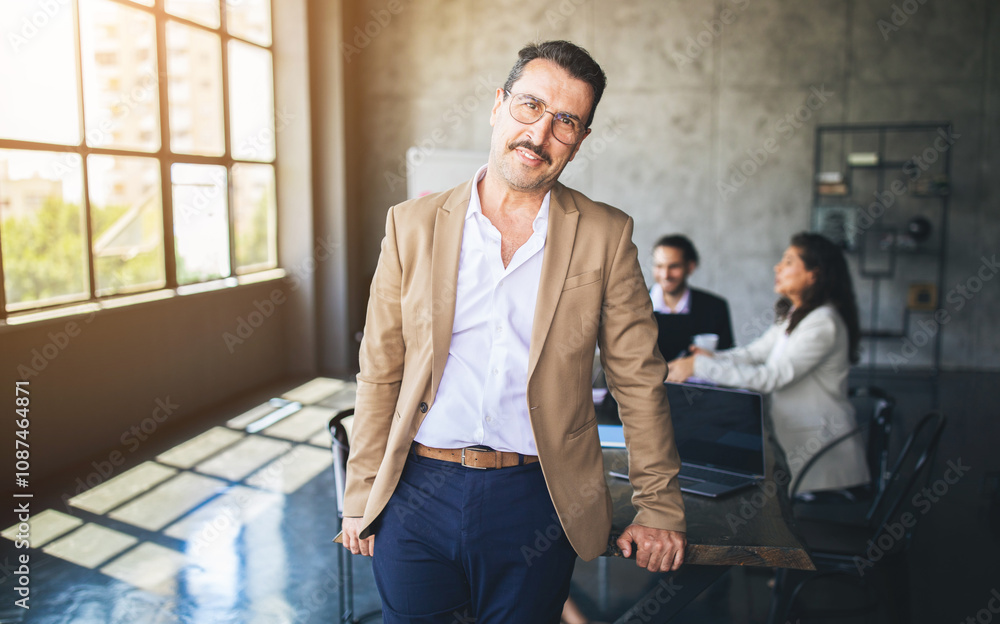 Aufkleber a man in business attire stands confidently at a large table, while two colleagues discuss ideas in 