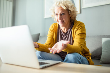 Woman online shopping with laptop on couch at home