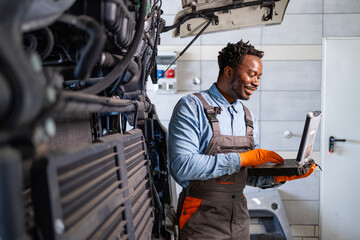 Truck mechanic repairing the engine with laptop diagnostic tool. Truck service and maintenance.