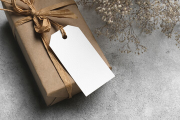 Blank gift tag or greeting label mockup with copy space, gift box with dry gypsophila flowers decor...