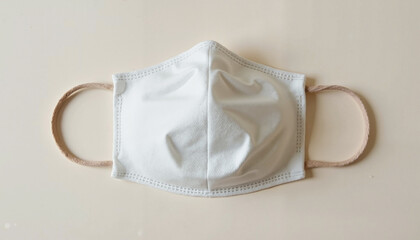 White face mask laid flat on a light background with copy space