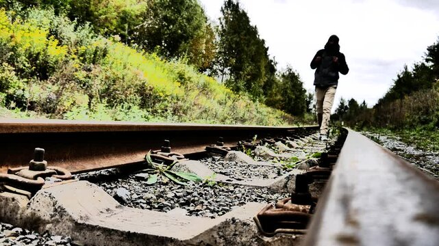 Close-up of old railway rails and a traveler walking along them