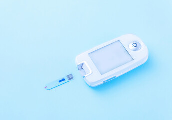 Fototapeta premium Diabetes mellitus. Close-up of a glucometer - a medical device for measuring blood glucose levels on a blue background with copy space. Self-monitoring of your health. Lifestyle, insulin dependence