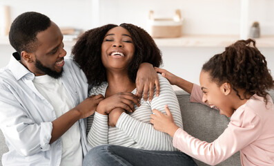 Having Fun Concept. Portrait of cheerful African American man, woman and girl playing at home...