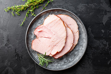 Sliced cold pork meat top view, boiled pork on a cutting board on black background copy space for...