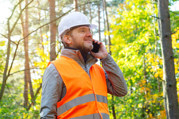Forestry engineer talks on his smartphone while working. Ecologist is conducting an environmental...