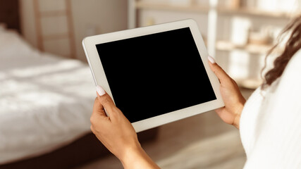 Over The Shoulder View Of Unrecognizable Black Woman Using Digital Tablet With Empty Screen Standing In Bedroom At Home. Application Or Internet Website Advertising, Mock Up, Free Space