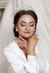 A woman wearing a tiara and a white dress. She is smiling and looking at the camera
